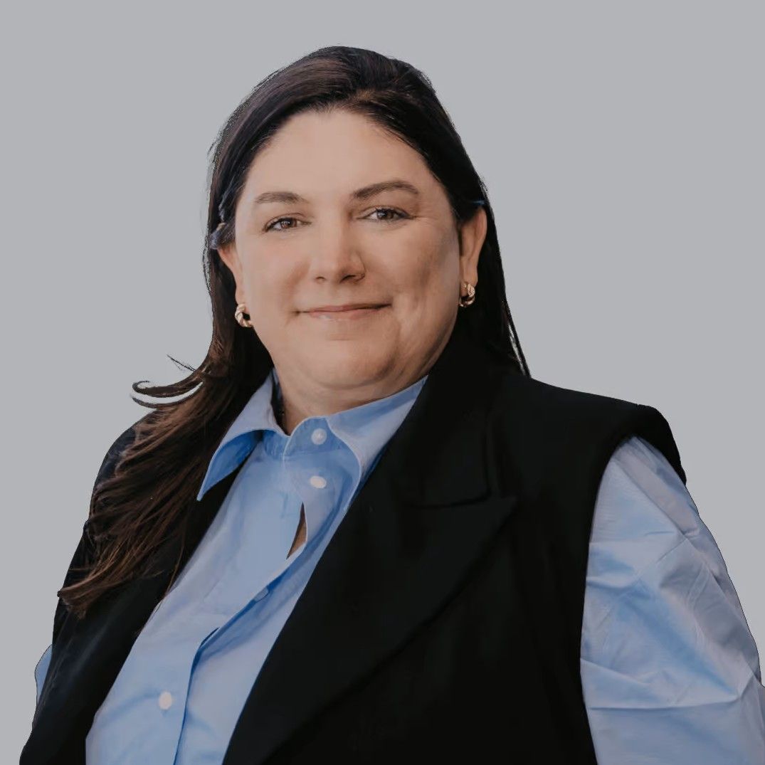 Kristin smirking at the camera in a blue dress shirt and black vest